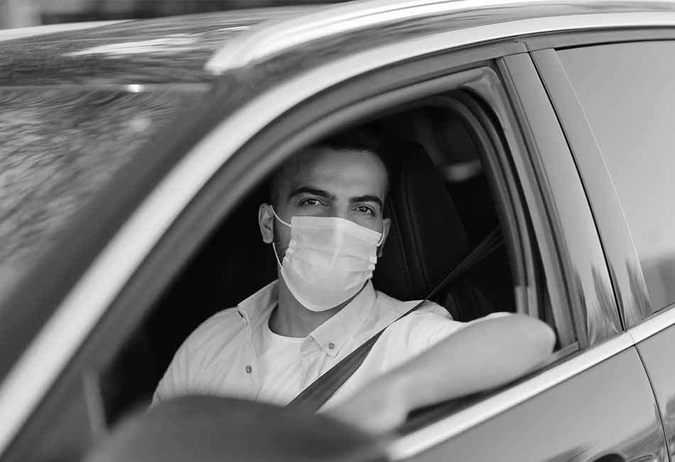 Driver in car wearing a safety mask