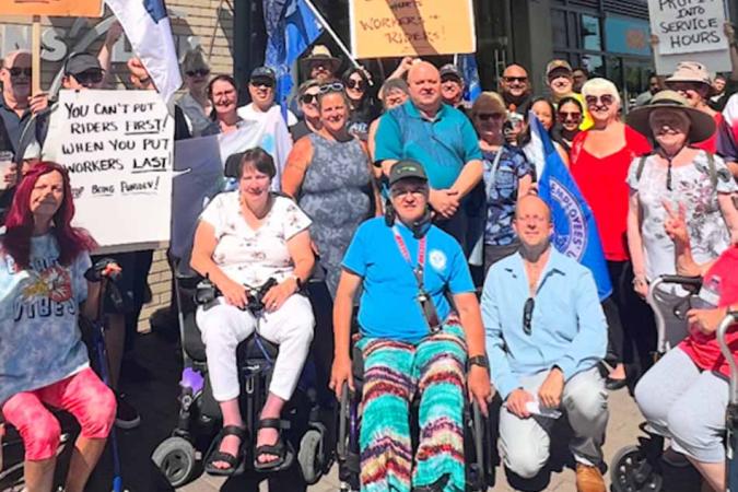 A group of protesters, many in wheelchairs, with signs supporting HandyDART service and workers